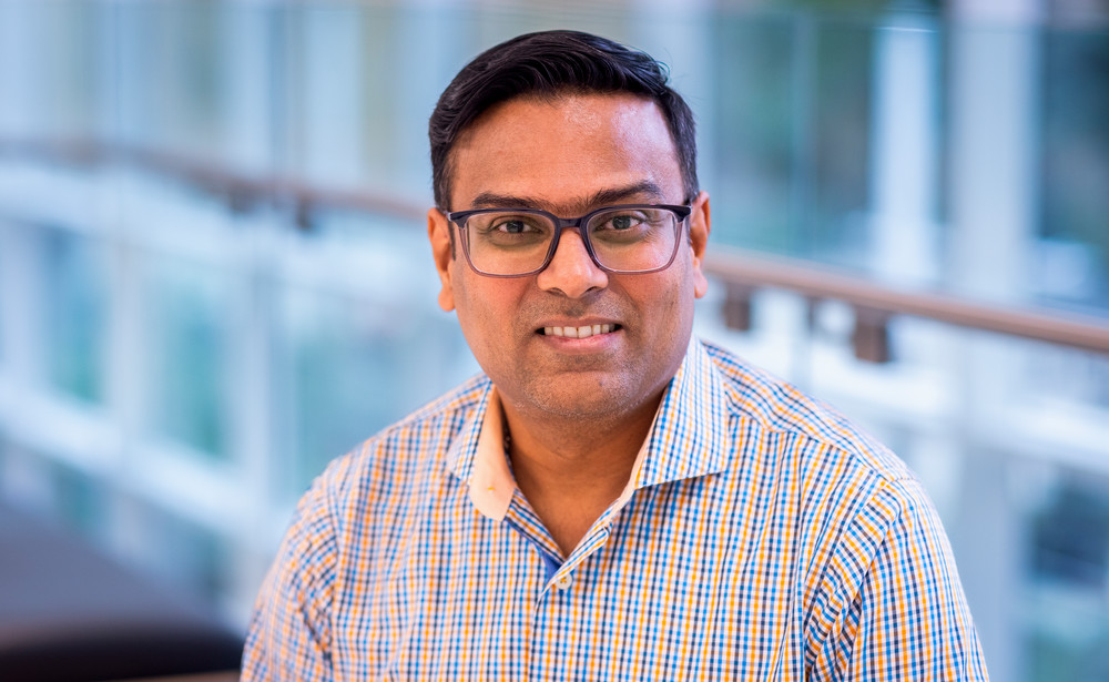 Headshot style photo of Rayan Chakraborty in a blue plaid button-up shirt.